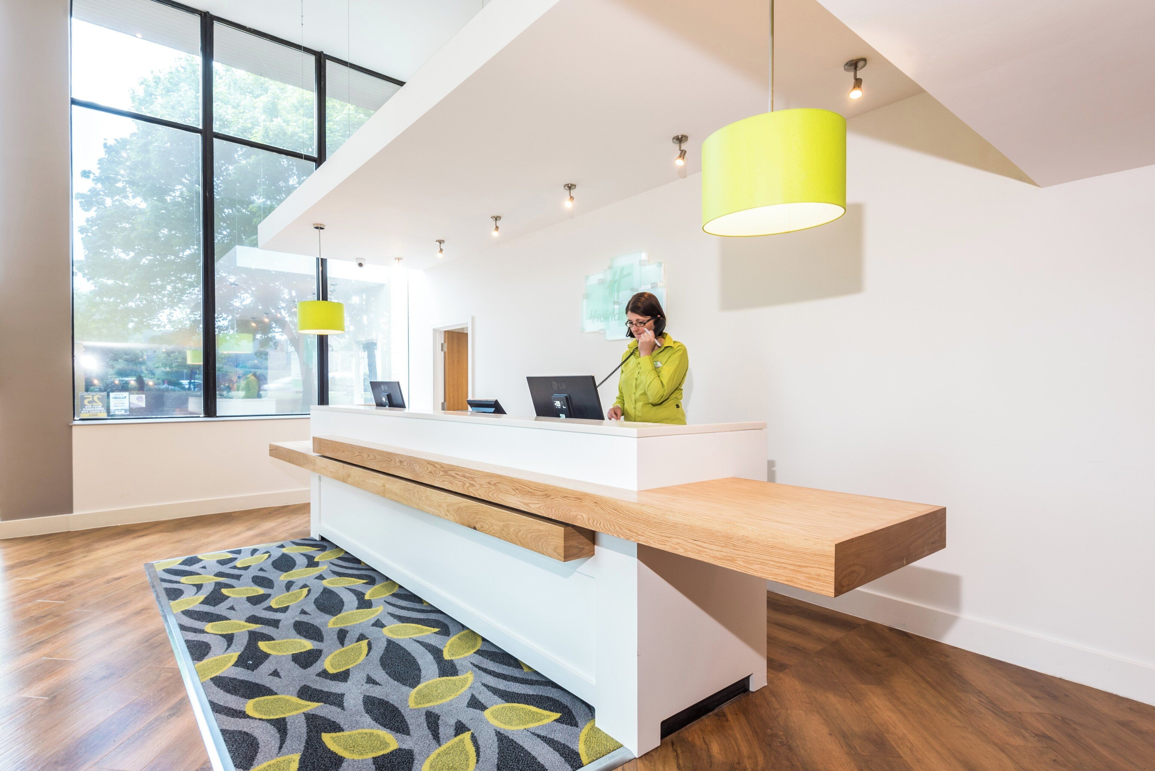 Un comptoir d’accueil au design moderne, une grande fenêtre et un tapis à motifs.