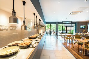 Zona de buffet amb diverses opcions gastronòmiques, una pantalla de televisió i vistes a l'exterior.