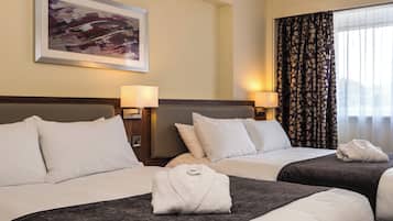 A hotel room with two beds, a painting on the wall, and a window with curtains.