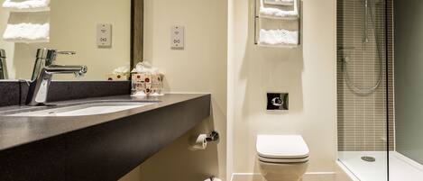 A modern bathroom with a black countertop sink, a toilet, and a glass-enclosed shower.