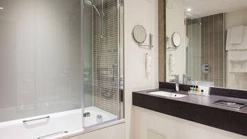 A modern bathroom with a glass-enclosed shower, a large mirror, and a black countertop.