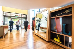 Un hall d’entrée avec un plancher en bois, un canapé, un miroir et une bibliothèque contenant divers objets.