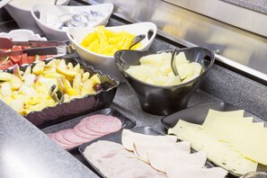 A buffet with various food items including fruits, cheeses, and meats.