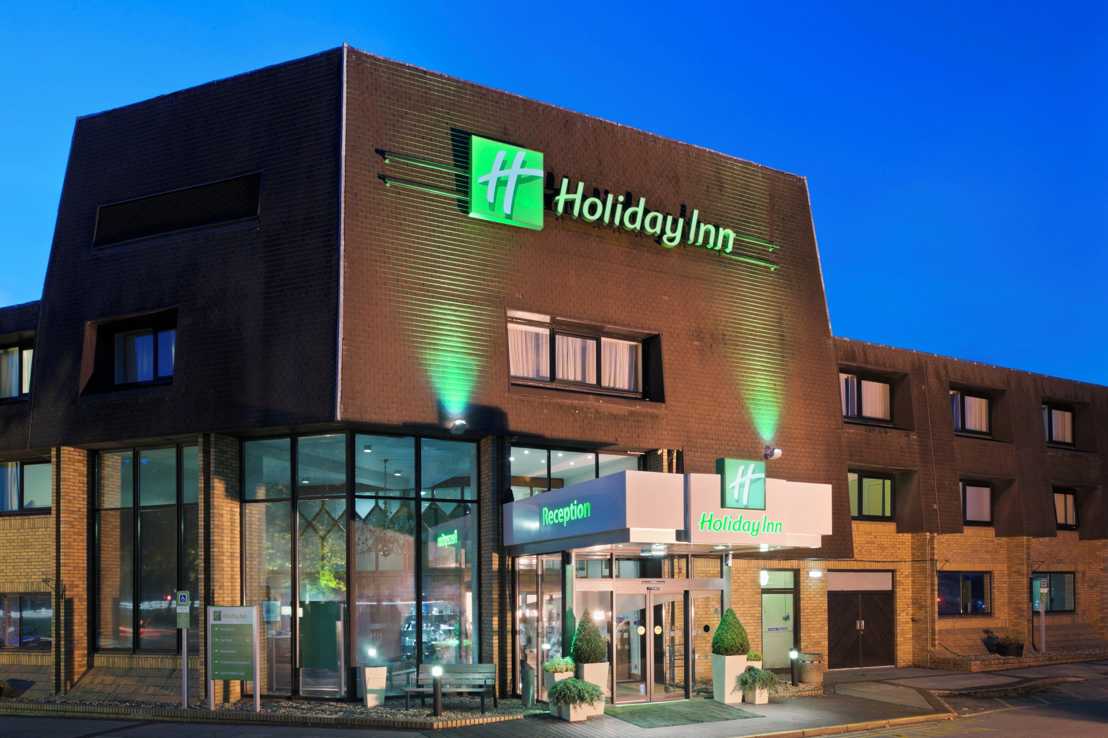A Holiday Inn hotel with a reception desk, a car park sign, and a sign for the restaurant.