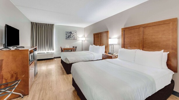 A hotel room with two beds, a desk, a television, and a window with curtains. - Quality Inn Easton (Easton)