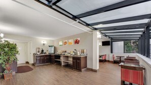 A spacious kitchen with a dining area, featuring a large window, a ceiling with exposed beams, and a countertop with various appliances. - Quality Inn Easton (Easton)