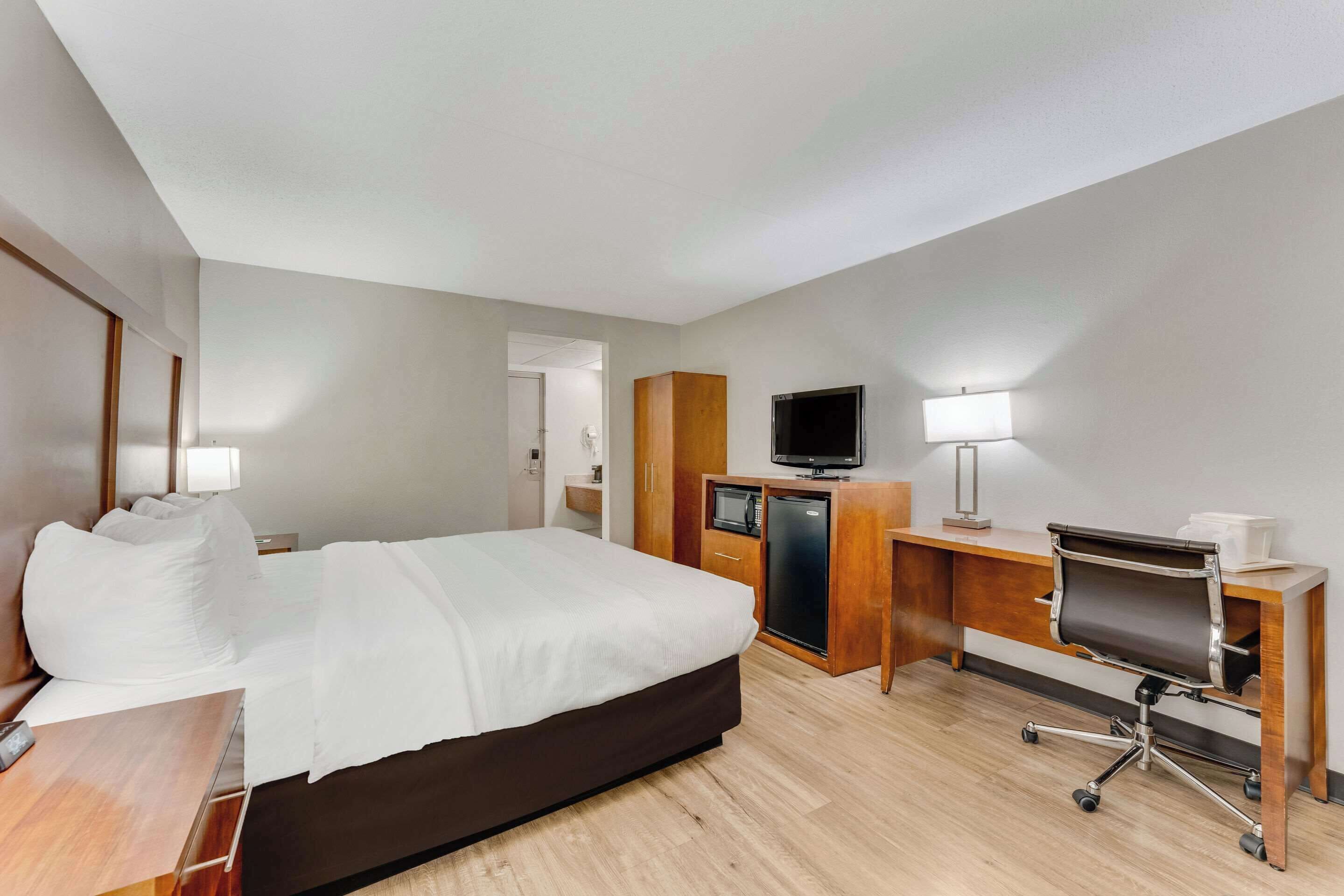 A hotel room with a bed, a desk with a computer, a television, and a microwave.