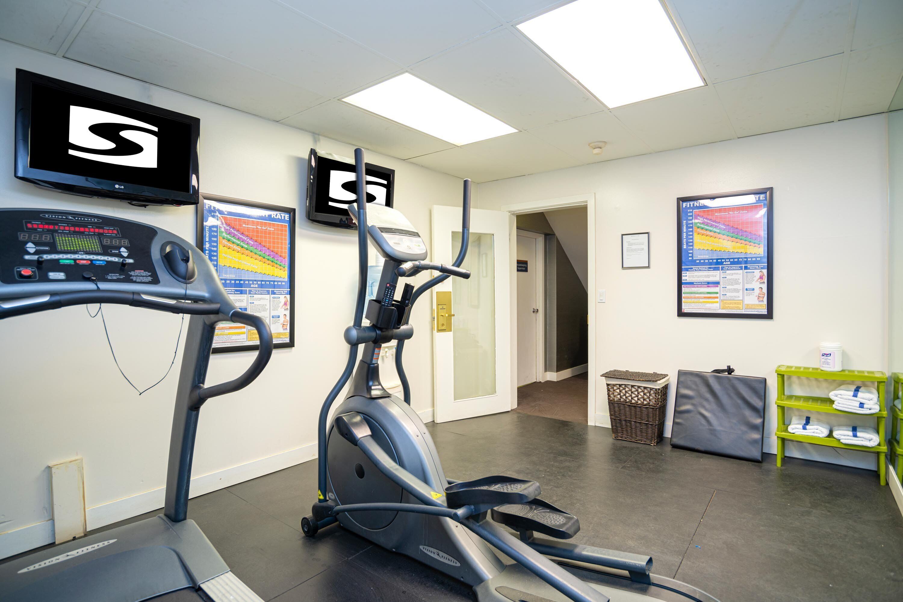 Une salle de sport équipée de tapis de course, d’un vélo d’appartement et d’un téléviseur fixé au mur.