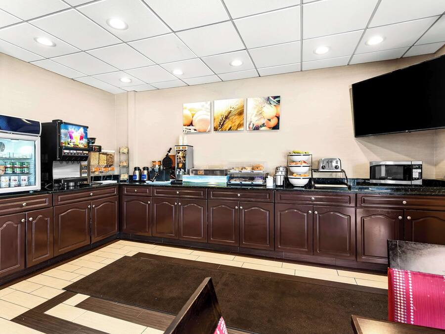 A kitchen area with a refrigerator, microwave, coffee machine, and a flat-screen TV mounted on the wall.