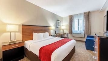 Habitación de hotel con una cama grande, mesitas de noche con lámparas, un escritorio, una silla y un televisor.