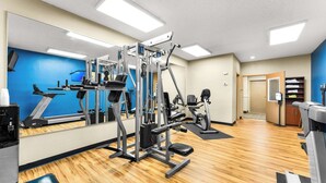 A gym with exercise equipment, a treadmill, and a mirrored wall.