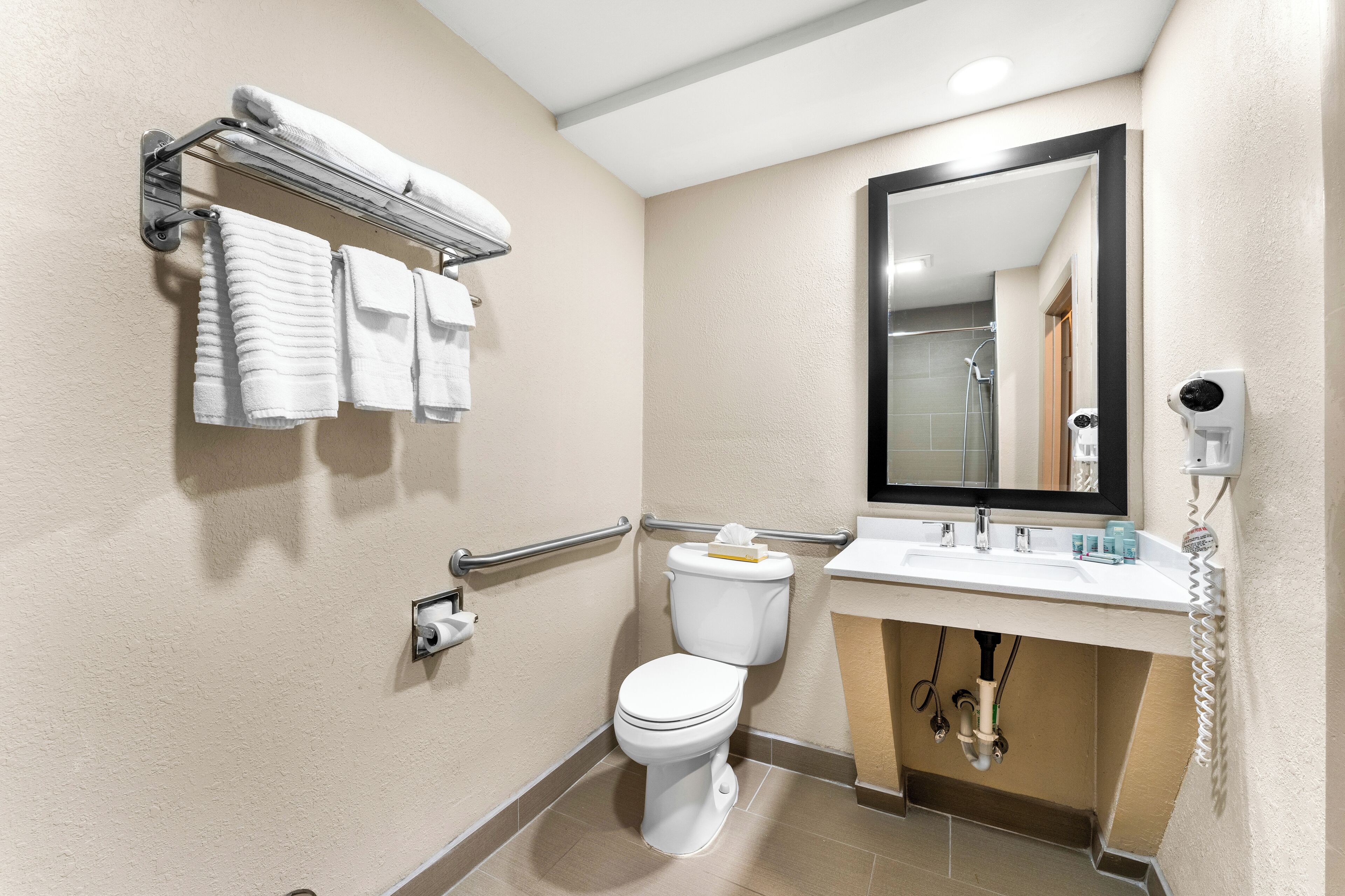 A modern bathroom with a toilet, sink, and hand dryer.
