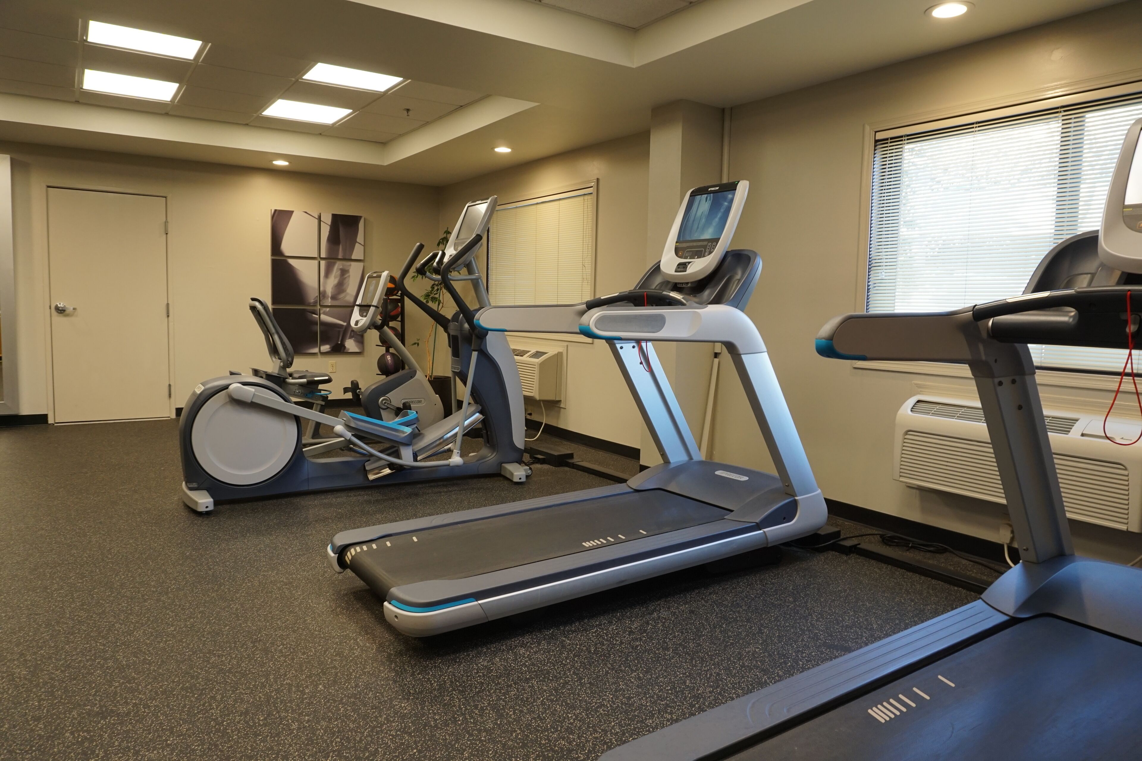 A fitness room with treadmills, elliptical machines, and a stationary bike.