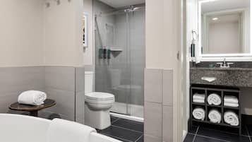 A modern bathroom with a glass-enclosed shower, a toilet, a bathtub, and a vanity with a towel rack.