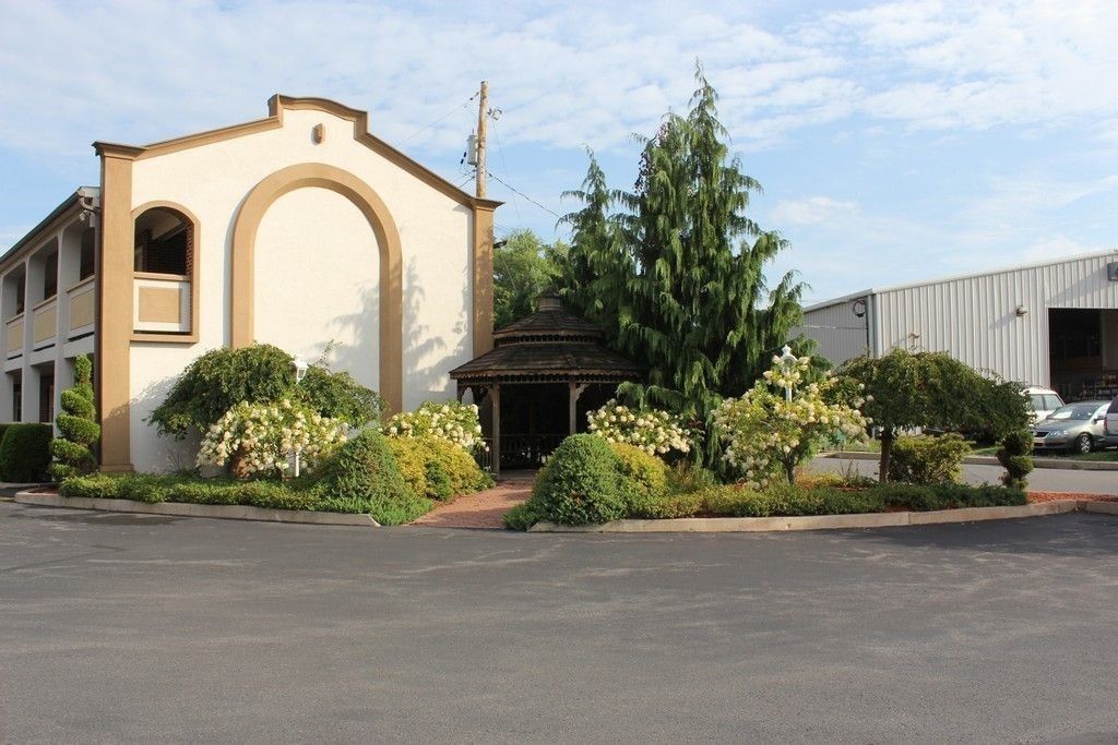 A building with a beige facade, a central arched entrance, and a small covered structure in front.