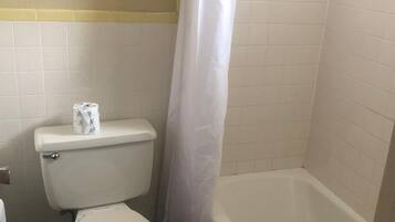 Et badeværelse med toilet, badekar og bruseforhæng.