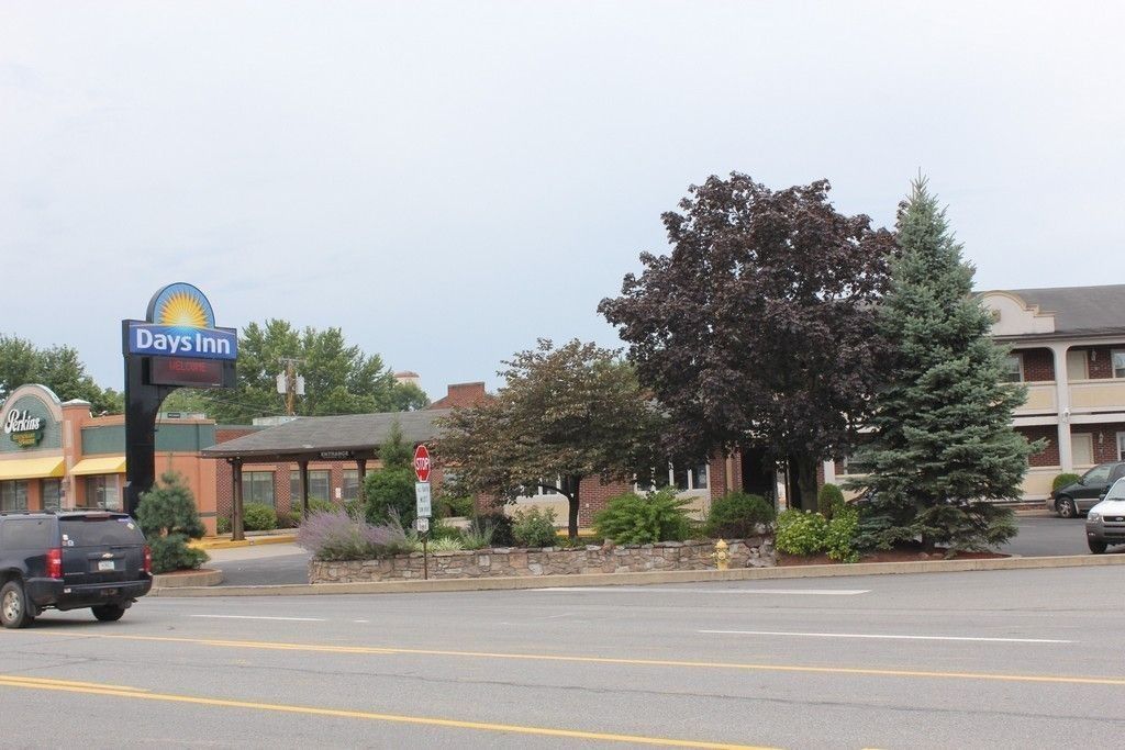 A Days Inn sign, a parking lot, a stop sign, and a building with a brick facade.