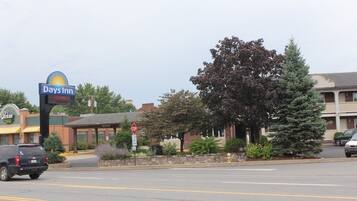 A Days Inn sign, a parking lot, a stop sign, and a building with a brick facade.