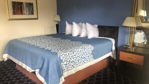 Una habitación de hotel con una cama grande, dos mesitas de noche y un espejo.