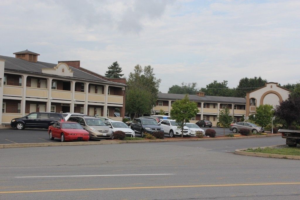 Un parcheggio con diverse auto parcheggiate di fronte a un motel a più piani e dal caratteristico stile architettonico.