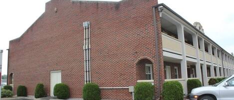 Un edificio de ladrillo rojo con estacionamiento y un automóvil.