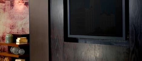 A modern interior with a wooden shelf displaying decorative items, a framed picture on the wall, and a textured wall surface.