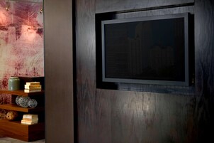 Un interior moderno con un estante de madera que exhibe objetos decorativos, un cuadro en la pared y una superficie mural con textura.