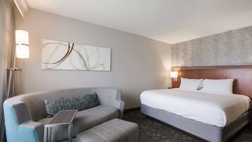 Een hotelkamer met een bed, een bank, een tafeltje en een kunstwerk aan de muur.
