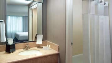 A hotel bathroom with a sink, mirror, and shower curtain.