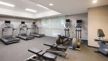 A gym with treadmills, elliptical machines, and weight benches.