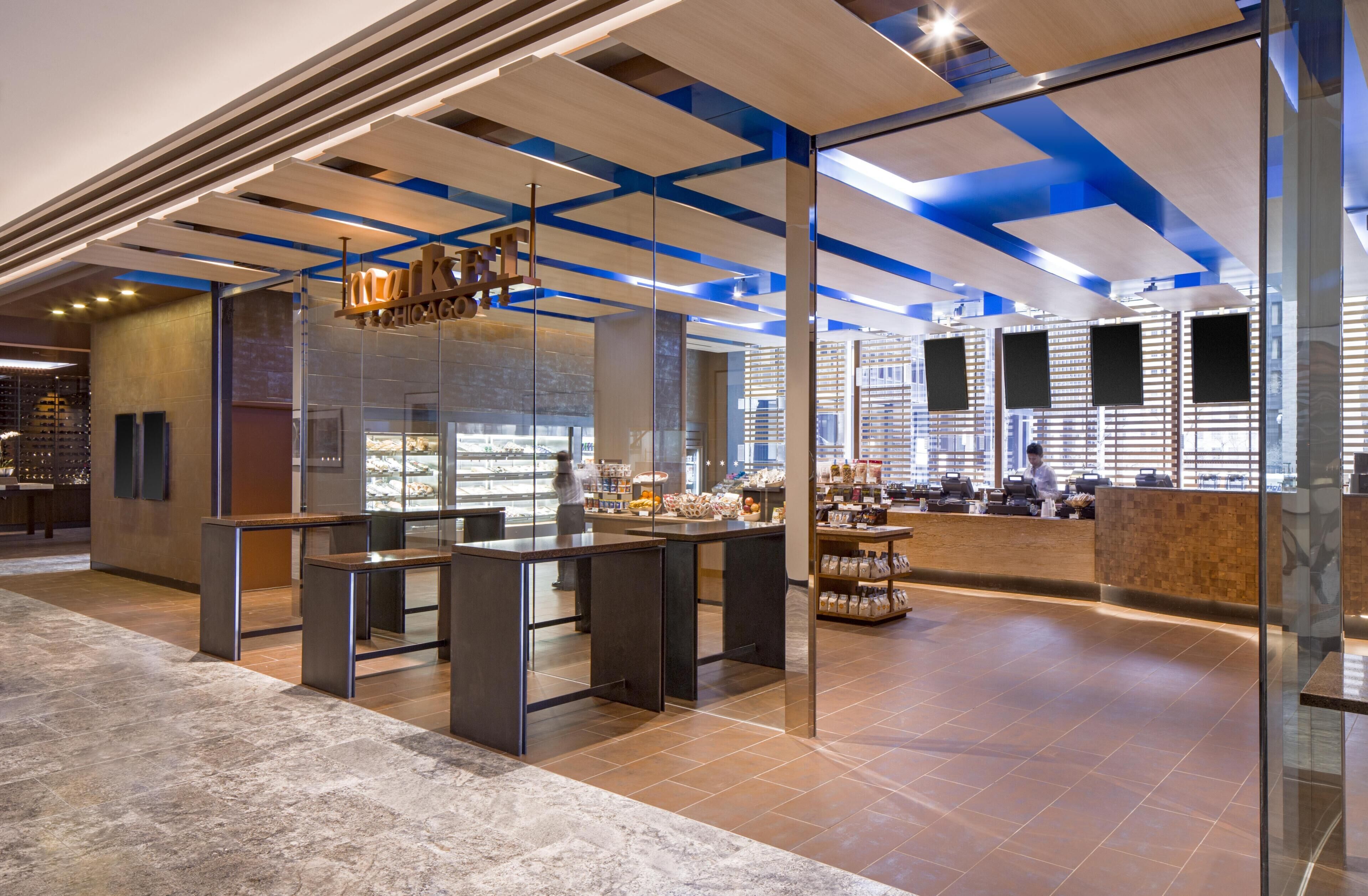 Un intérieur moderne avec des cloisons en verre, un espace cuisine et un coin salon avec des tables et des chaises.