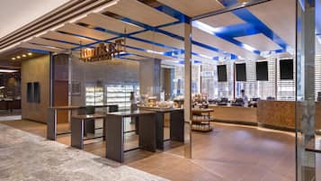 Un intérieur moderne avec des cloisons en verre, un espace cuisine et un coin salon avec des tables et des chaises.
