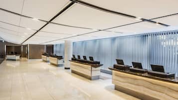 A modern hotel reception area with multiple counters, a polished floor, and a ceiling with linear lighting.