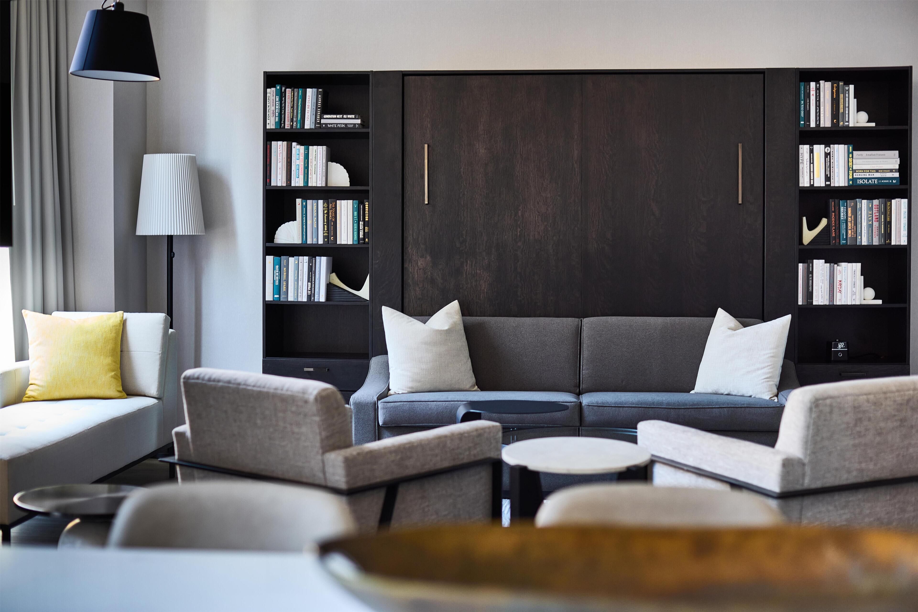 A modern living room with a sofa, armchairs, a coffee table, and a bookshelf.