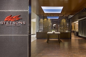 A modern interior with a branded sign, a wine rack, and a table with a vase.