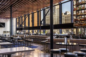 A spacious bar area with high ceilings and large windows, offering views of a cityscape. - Hyatt Regency Chicago (Chicago)