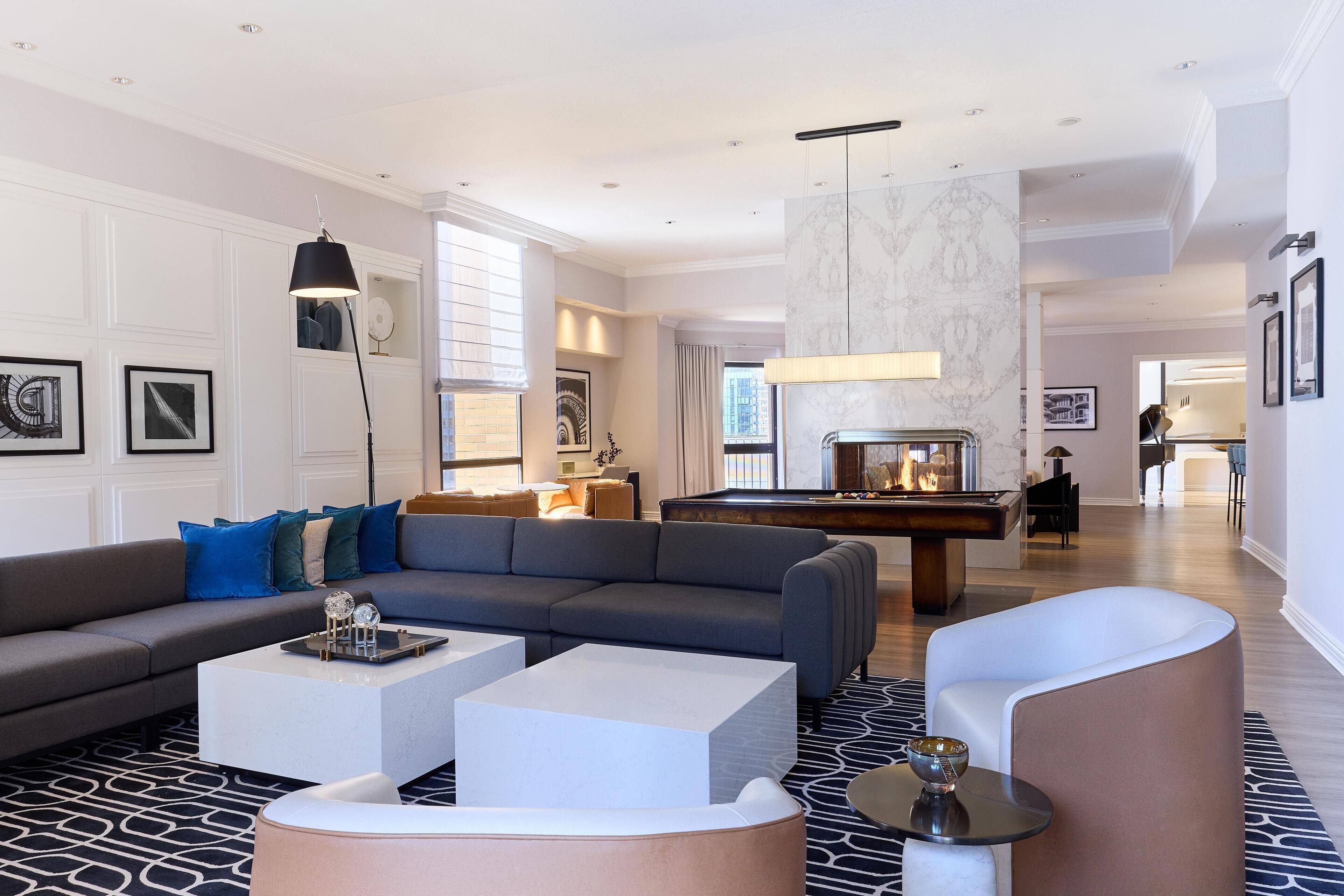 A modern living room with a sofa, coffee table, and a pool table.