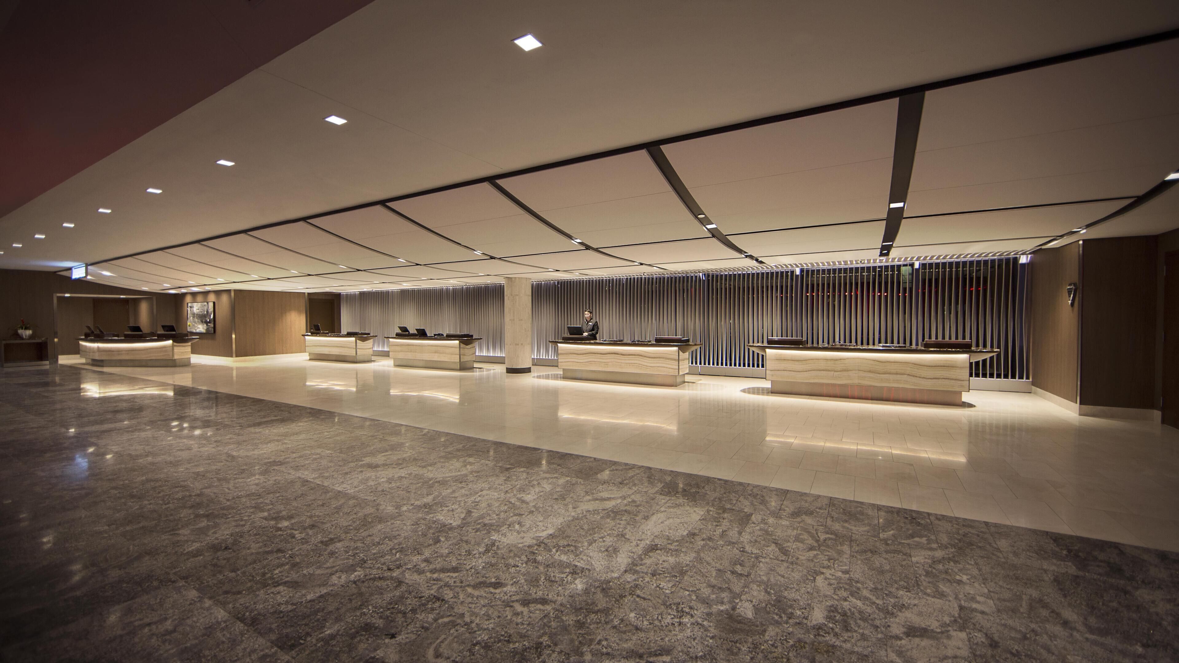 A spacious lobby with multiple reception desks, a polished marble floor, and a modern ceiling design.