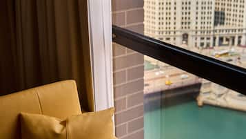 Una habitación con vistas a un paisaje urbano a través de una ventana, un sofá con un cojín y una pared de ladrillo.