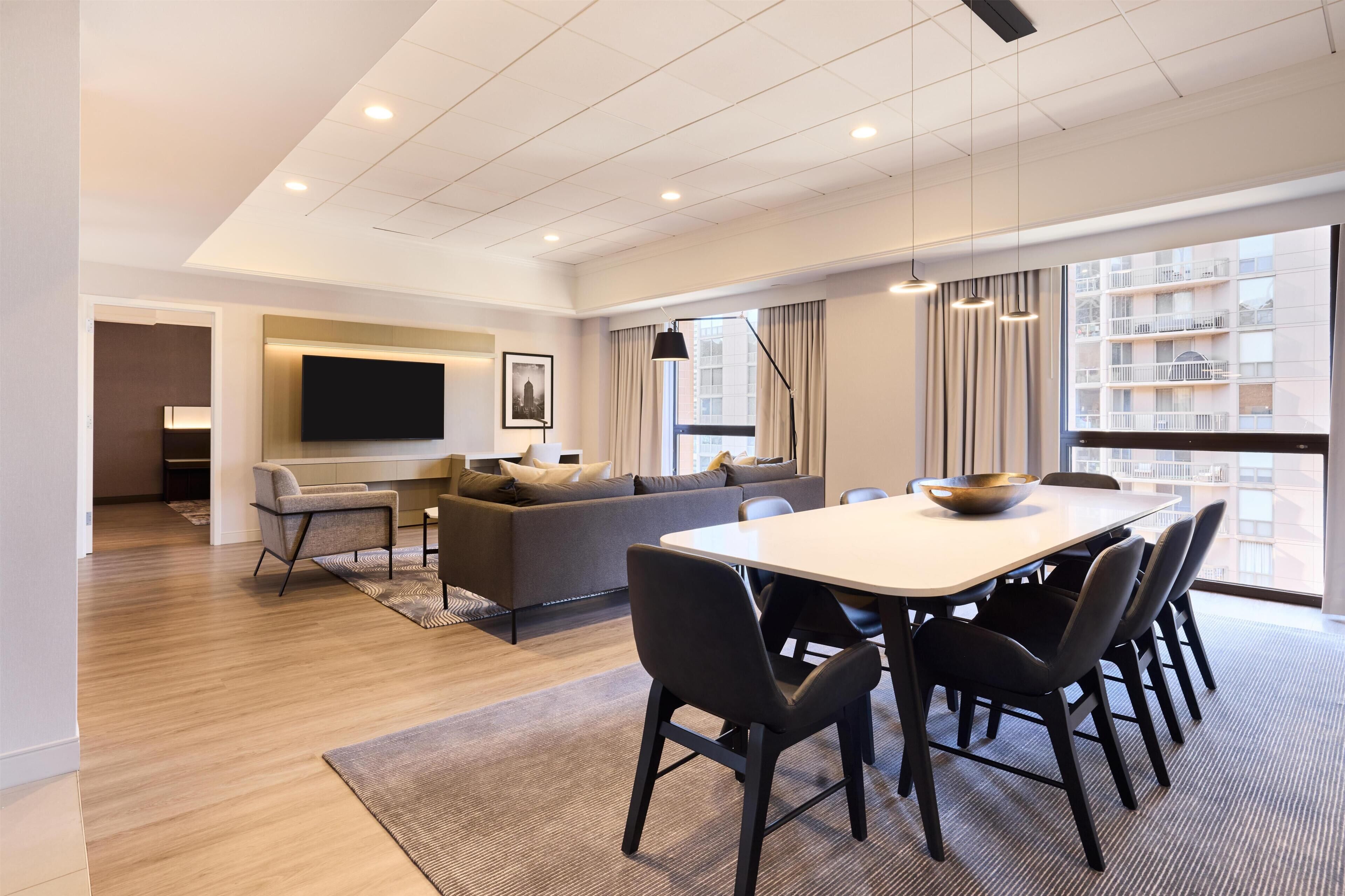 A modern living room with a sofa, TV, dining table, and chairs.