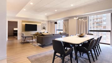 A modern living room with a sofa, TV, dining table, and chairs.