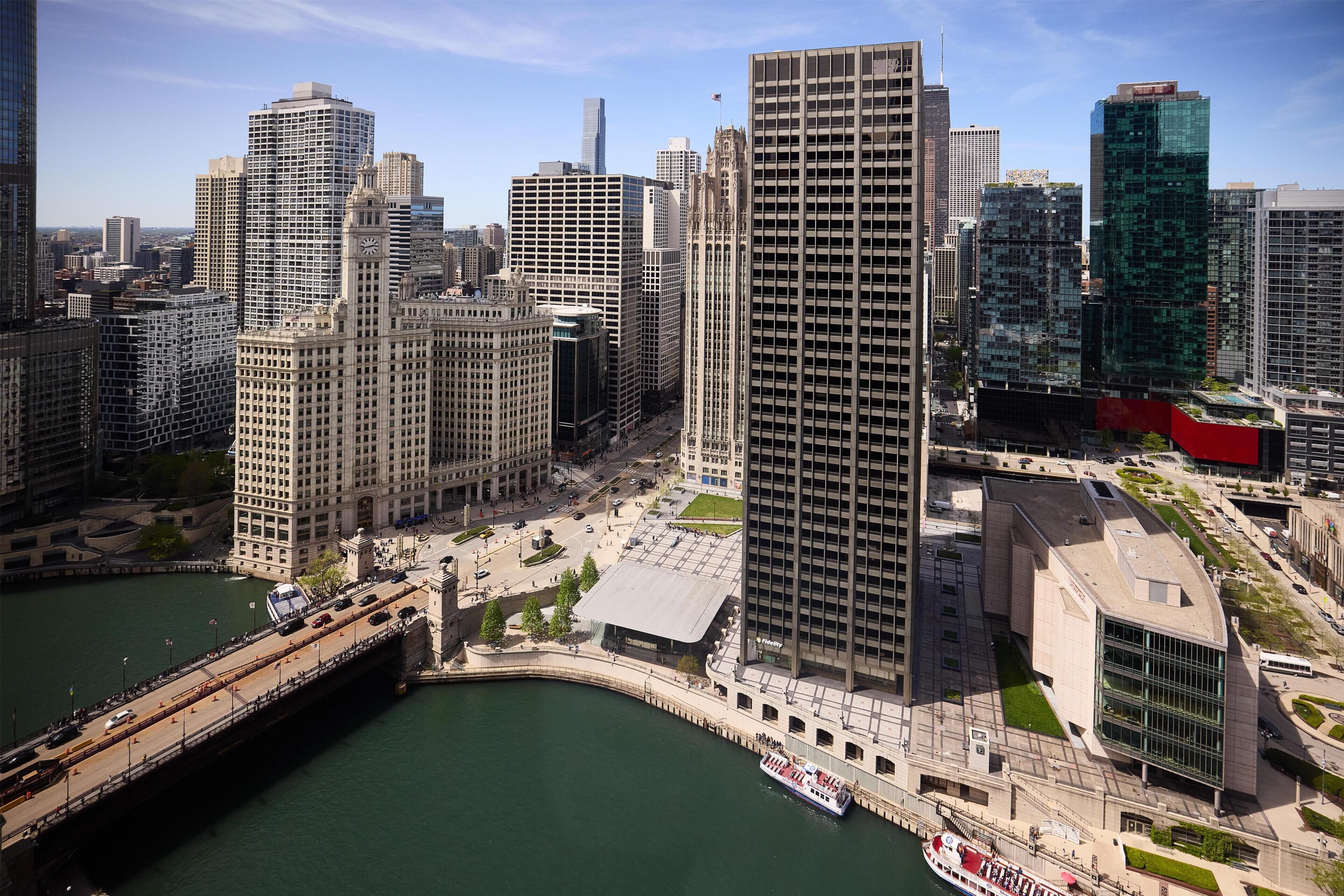 A high-rise building with a modern glass facade, surrounded by other tall buildings and a river.