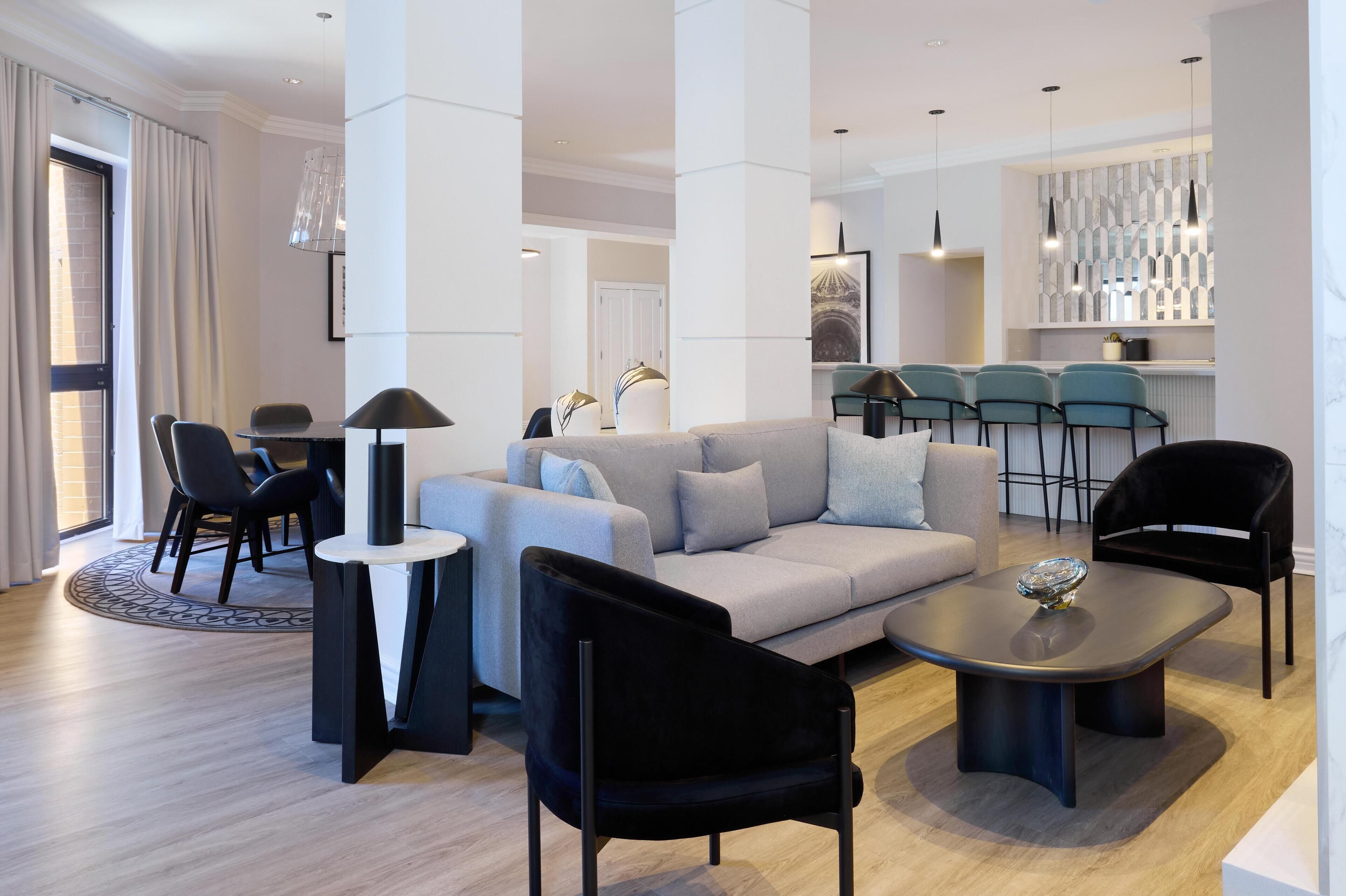 A modern living room with a sofa, chairs, a coffee table, and a dining area with a table and chairs.