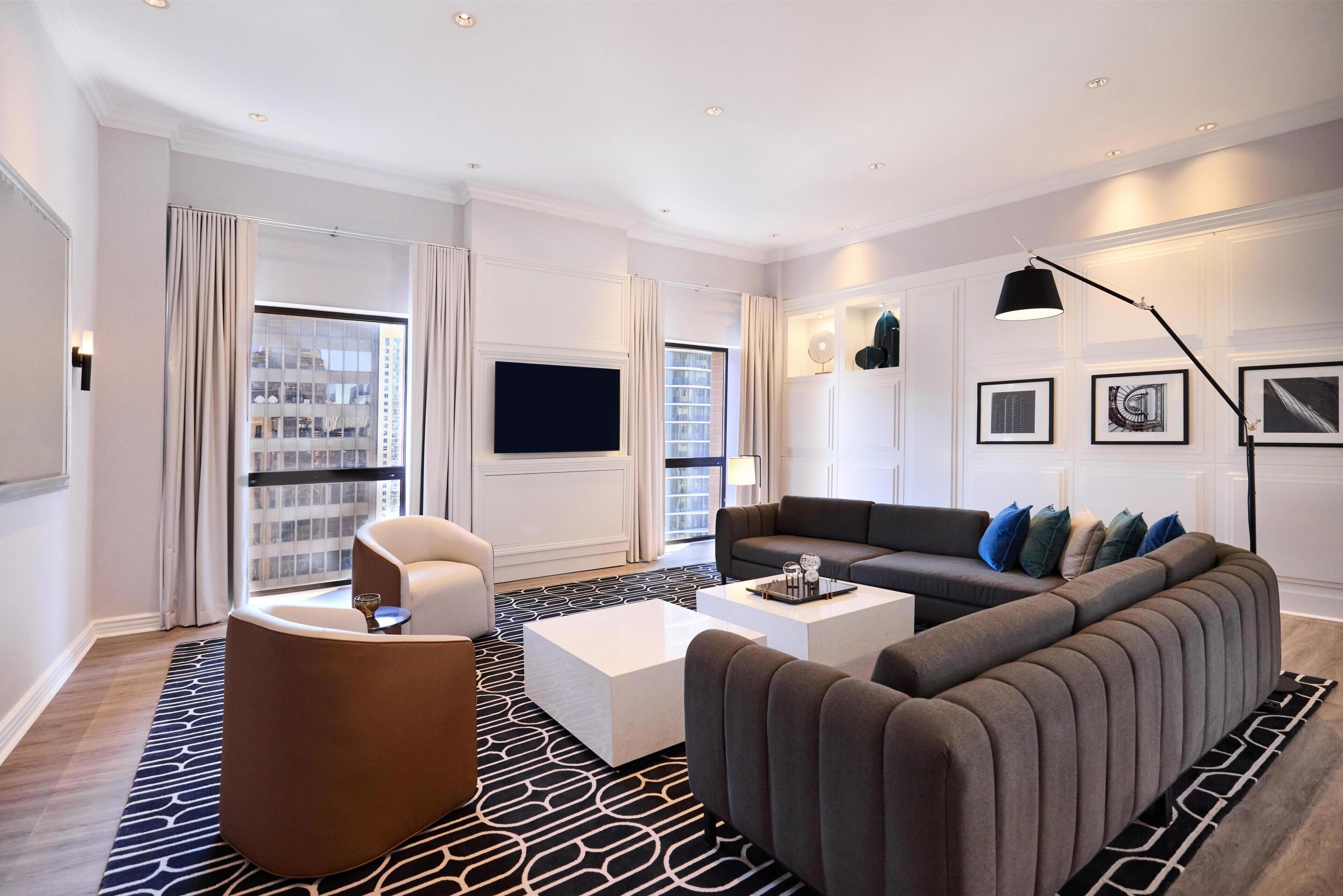 Un salon moderne avec un canapé, des fauteuils, une table basse et un téléviseur.