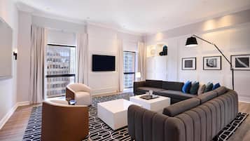 Un salon moderne avec un canapé, des fauteuils, une table basse et un téléviseur.