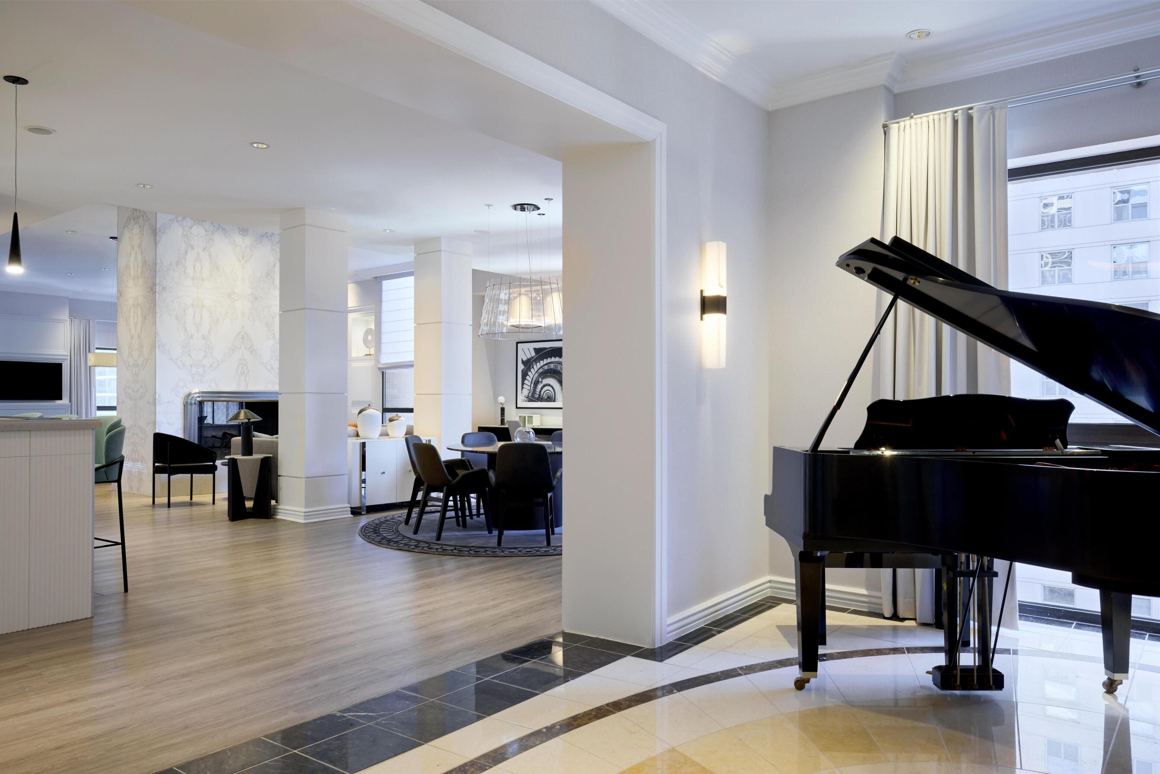 A spacious living area with a grand piano, a dining area, and a kitchen.