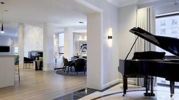 A spacious living area with a grand piano, a dining area, and a kitchen.
