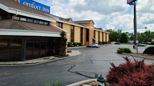 Un hotel Comfort Inn con un diseño moderno, que cuenta con un letrero grande, un estacionamiento y un cielo despejado.