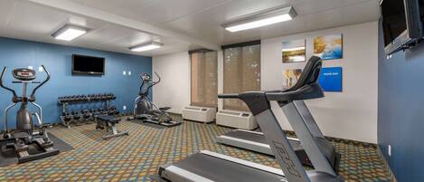 A gym with treadmills, elliptical machines, and free weights.