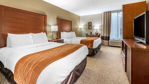 Habitación de hotel con dos camas, un televisor, un escritorio y una ventana con cortinas.